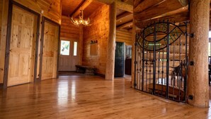 A log cabin interior with wooden floors, a chandelier, and a metal gate.