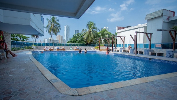 A swimming pool with lounge chairs and palm trees in the background. - Apartamento con vista al mar Cartagena (Cartagena)