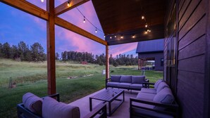 An outdoor patio with a wooden pergola, seating area, and string lights.