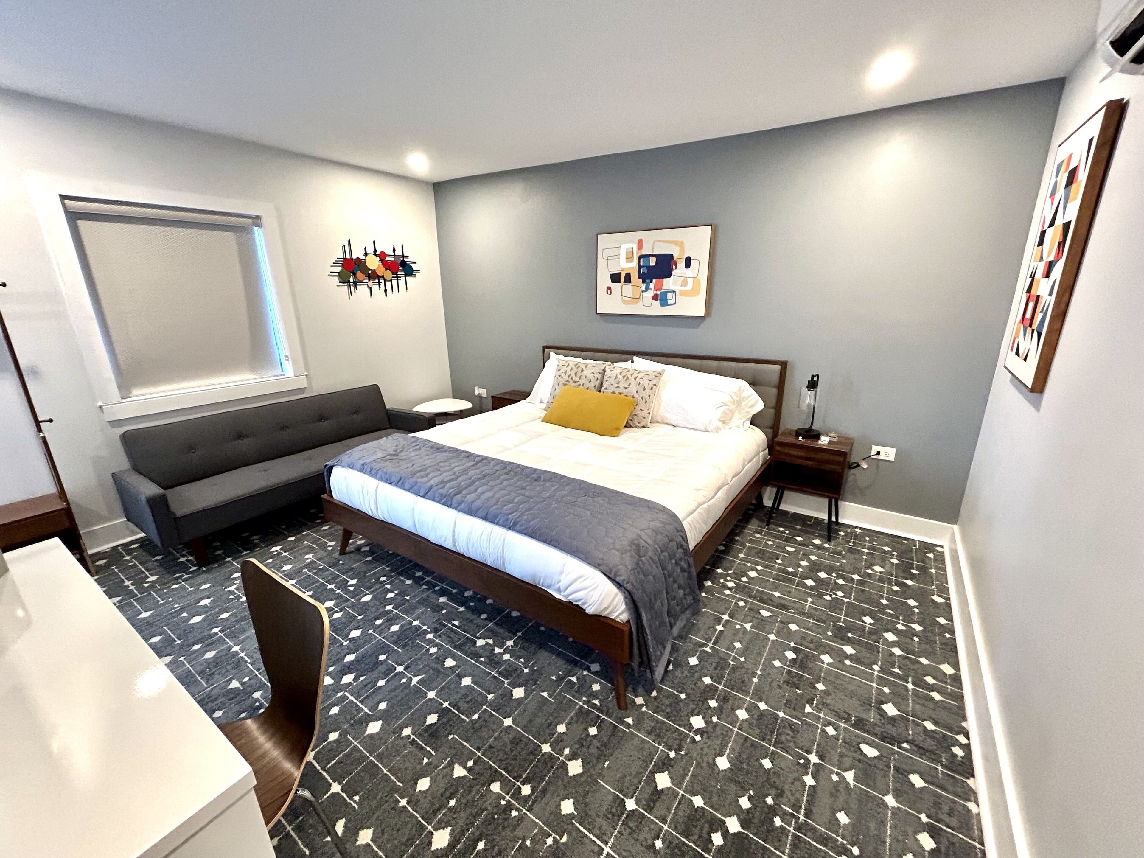 Une chambre moderne avec un lit, un canapé, un bureau et un sol à motifs.
