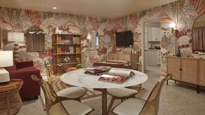 A living room with a round table, four chairs, a sofa, a bookshelf, and a TV. - New South Motor Inn (Madison)