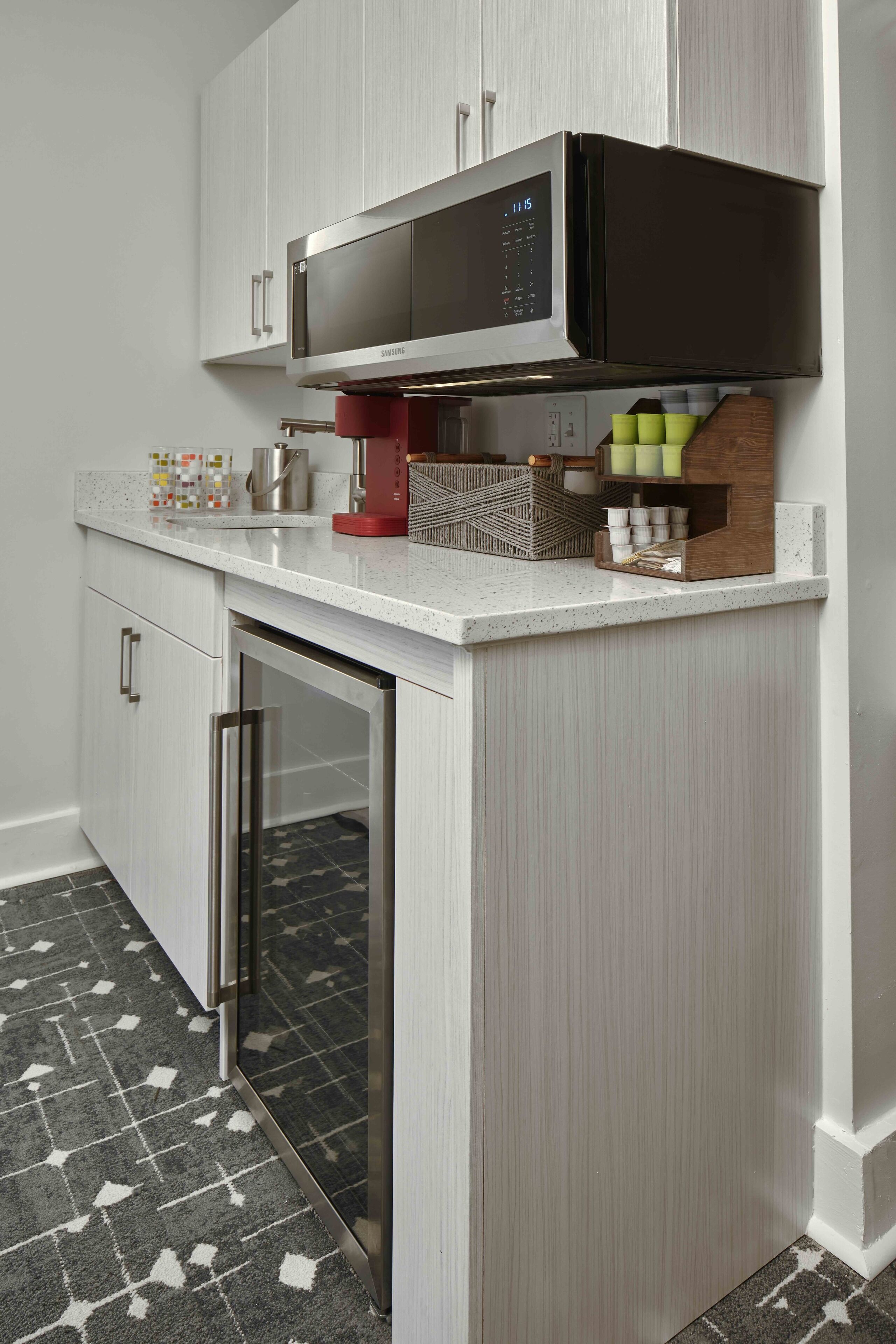 A kitchen with a built-in microwave, stainless steel appliances, and a patterned floor.
