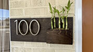 A house number sign with a wooden background and three bamboo plants.