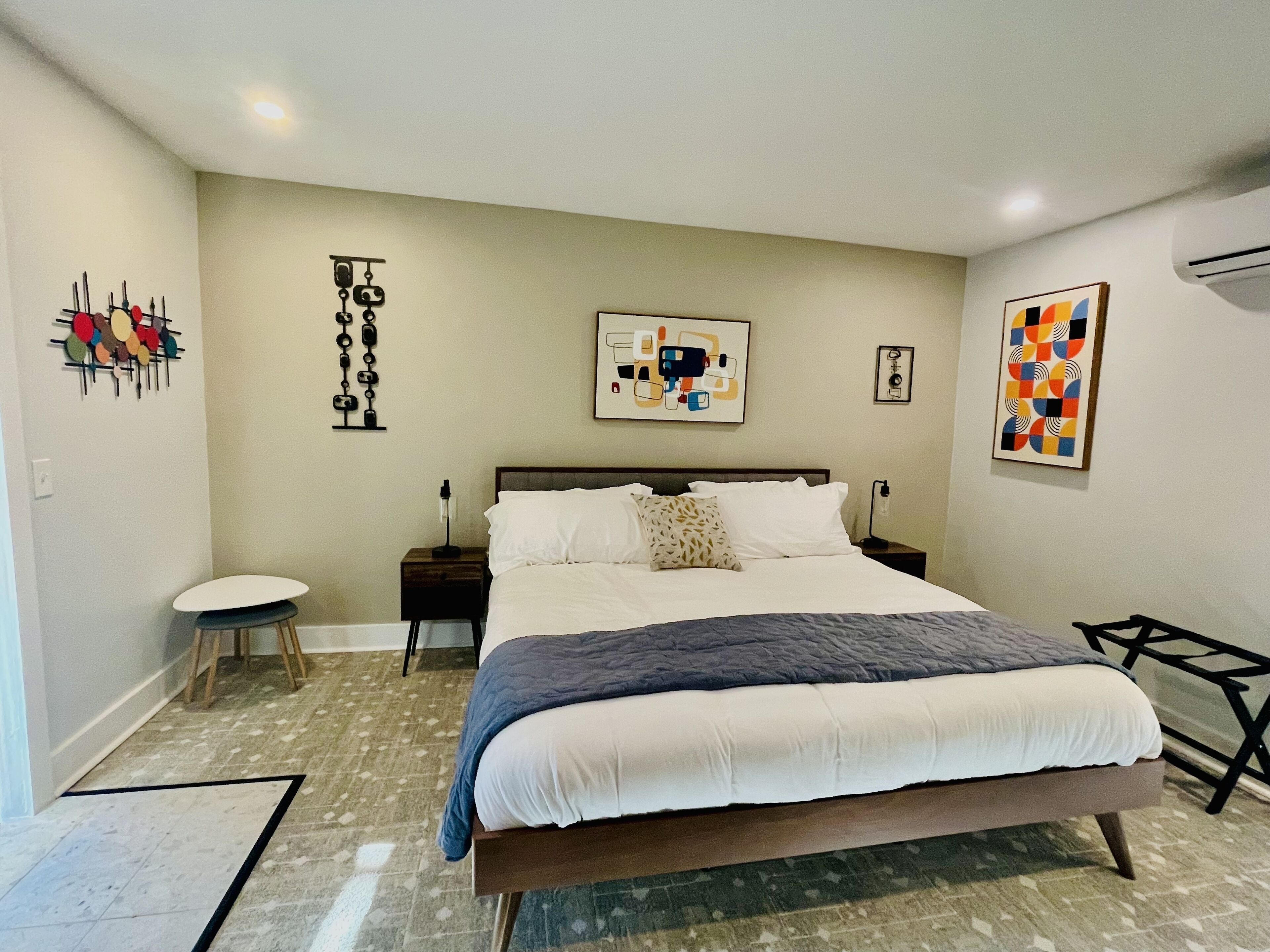 Un dormitorio con una cama grande, una mesita de noche, una silla y decoración en la pared.