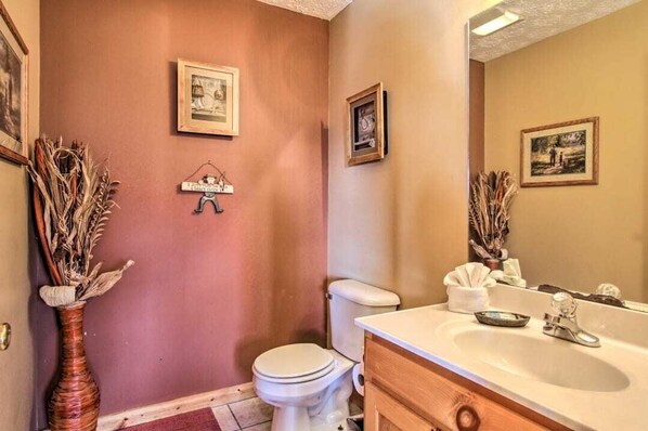 A bathroom with a toilet, sink, and two framed pictures on the wall. - Unforgettable Views, Great for groups & Families (Sevierville)
