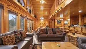 A cozy cabin interior with a leather sofa, wooden dining table, and a ceiling fan.