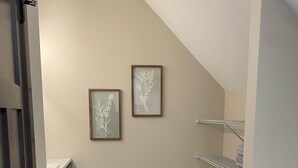 A modern bathroom with a sloped ceiling, two framed wall art pieces, a built-in shelf, and a tiled floor. - Custer's Retreat - 2 BD Cabin (Custer)