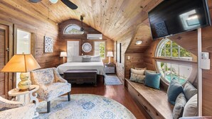A cozy cabin interior with a bed, seating area, and a TV. - 3 Bedroom Home - Perfect Location & Private Pool (Key West)