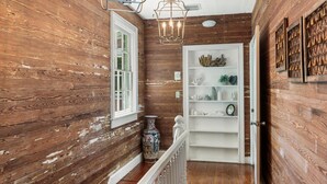 A wooden interior with a white door, a white railing, and a chandelier. - 3 Bedroom Home - Perfect Location & Private Pool (Key West)