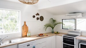 Een moderne keuken met witte kasten, een ingebouwde vaatwasser, een fornuis en een groot raam dat voor daglicht zorgt.