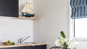 Een moderne keuken met een houten aanrecht, een model zeilbootje, een vaas met bloemen en een ronde tafel met stoelen.