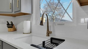 Una cucina con un lavello in acciaio inossidabile, una finestra vista alberi e un portacoltelli sul piano di lavoro.