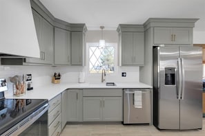 A modern kitchen with grey cabinets, a stainless steel refrigerator, and a built-in oven. - Walk to Restaurants | Sleeps a Crowd | Bourbon Trail Base (Louisville)