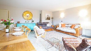 Ein modernes Wohnzimmer mit einem Holzesstisch, der für eine Mahlzeit gedeckt ist, einer Couch und einem Couchtisch.