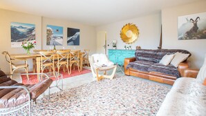 Ein Wohnzimmer mit einer Couch, Sesseln, einem Esstisch und Kunstwerken an den Wänden.
