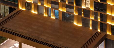 A modern building with a flat roof, multiple windows, and a well-lit entrance area.