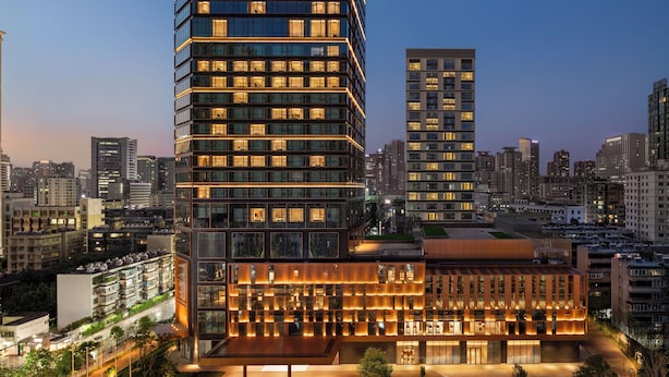 Un hotel moderno de rascacielos con varios pisos, ventanas amplias y un letrero destacado en la parte superior.