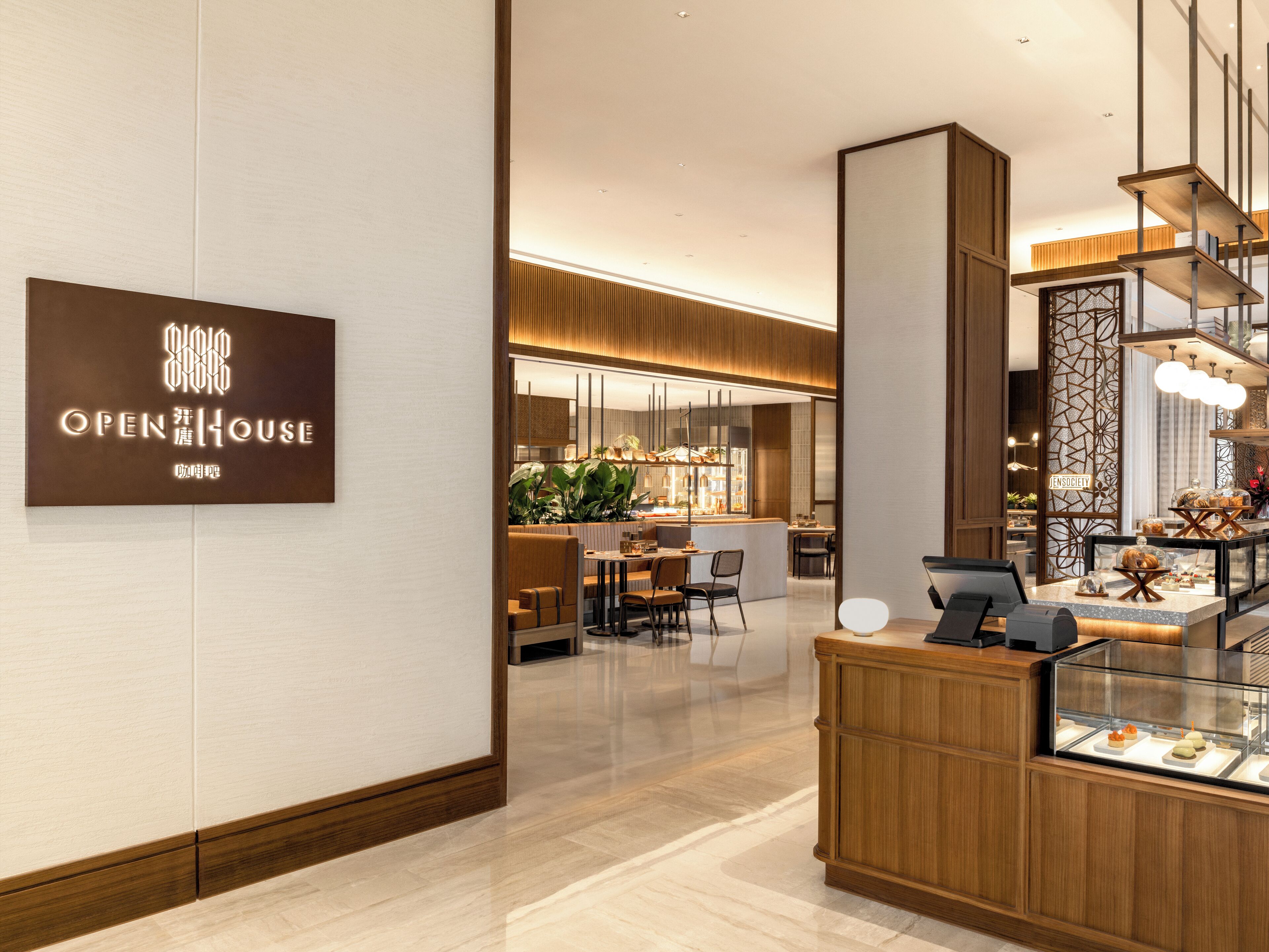 A modern hotel lobby with a reception desk, a seating area, and a bar.