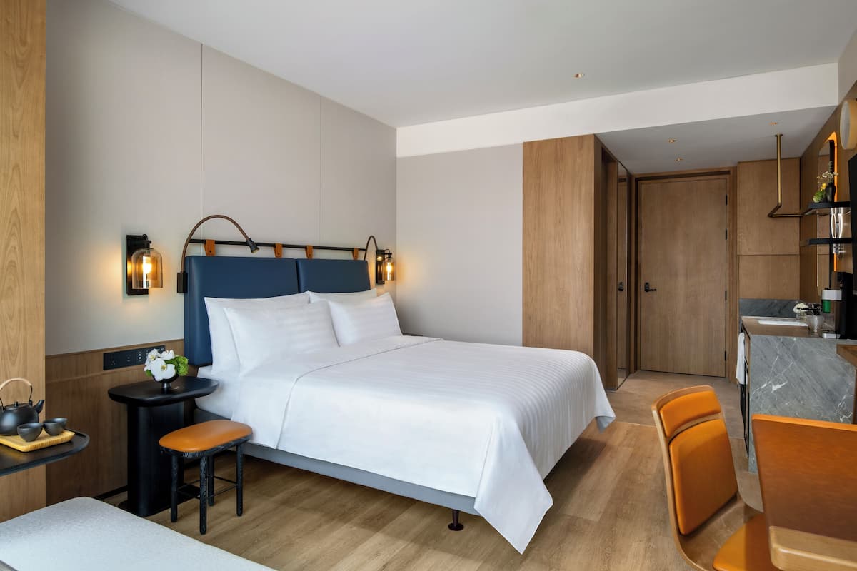 Une chambre d’hôtel moderne avec un grand lit, des tables de chevet, un bureau et une chaise.