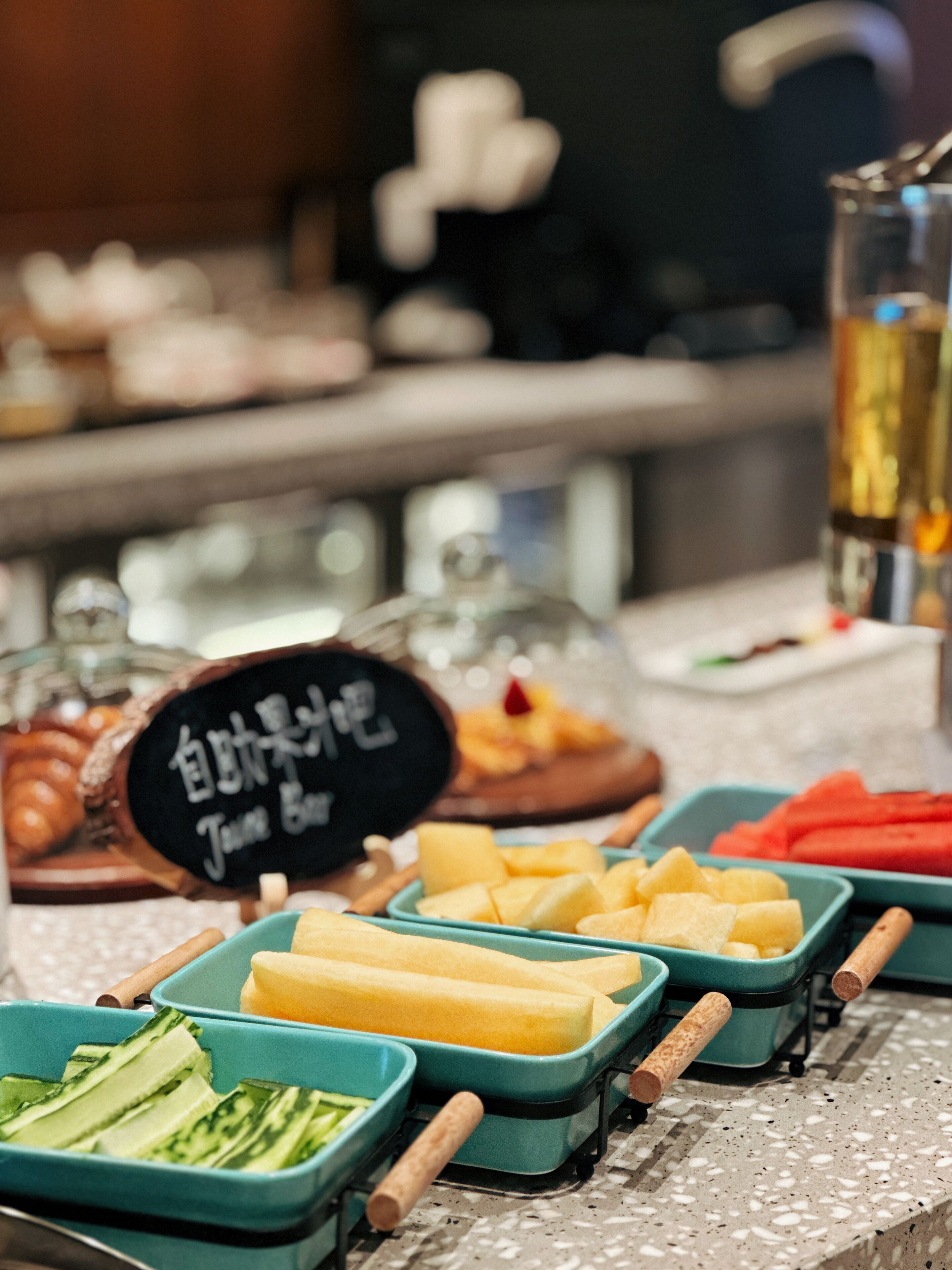 A buffet with various food items including fruits and vegetables in green trays.