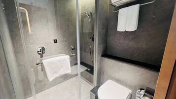 A modern bathroom with a glass-enclosed shower, a toilet, and a towel rack.