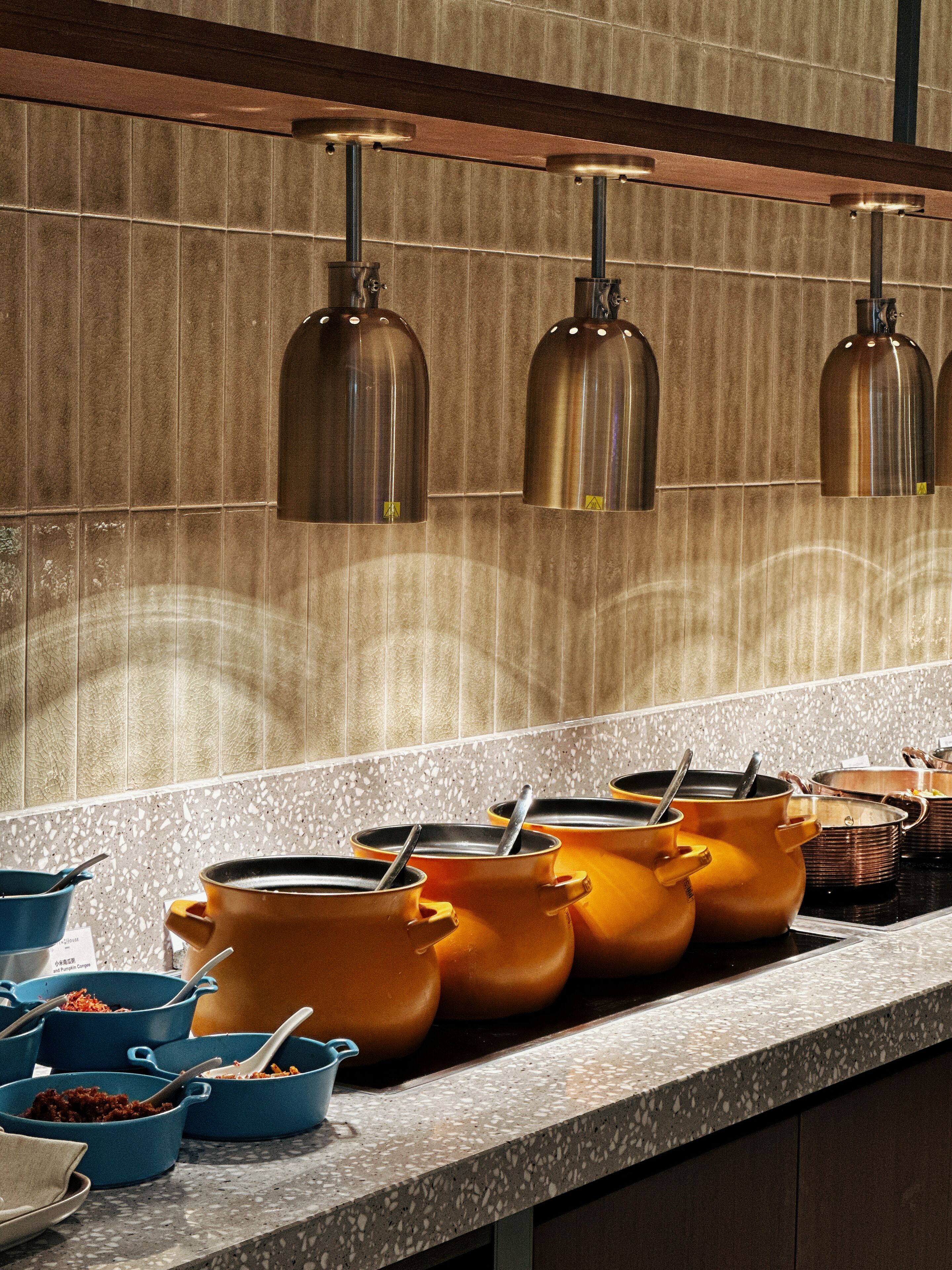 Una cucina con diverse pentole sul bancone, uno schienale e luci a sospensione.