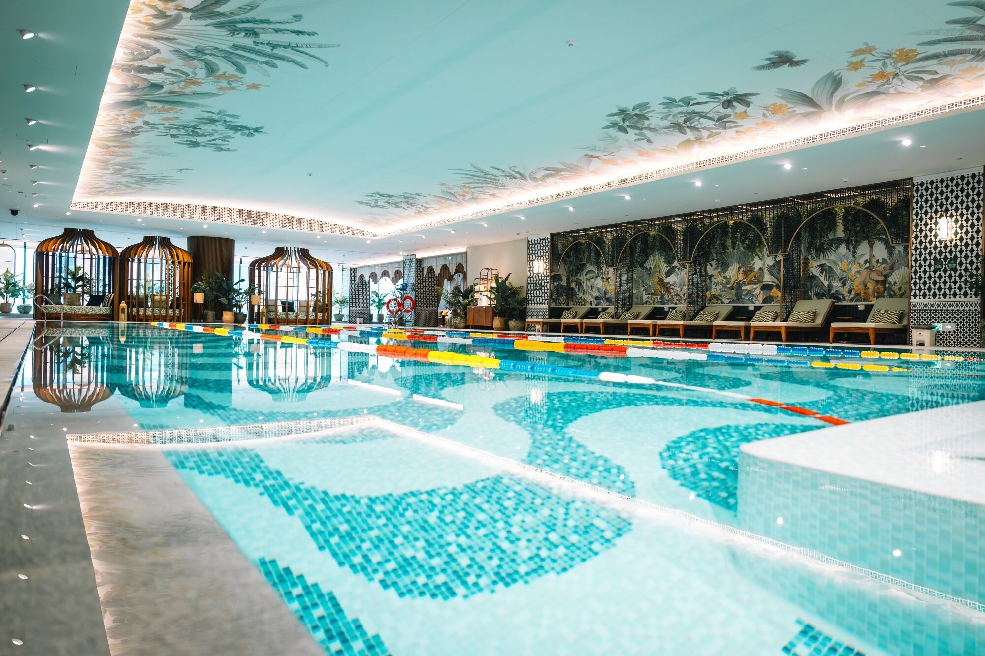 Une piscine à l’eau claire, entourée de chaises longues et agrémentée d’un plafond décoratif.