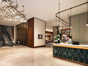 Un moderno vestíbulo de hotel con una recepción, una escalera y una lámpara decorativa.