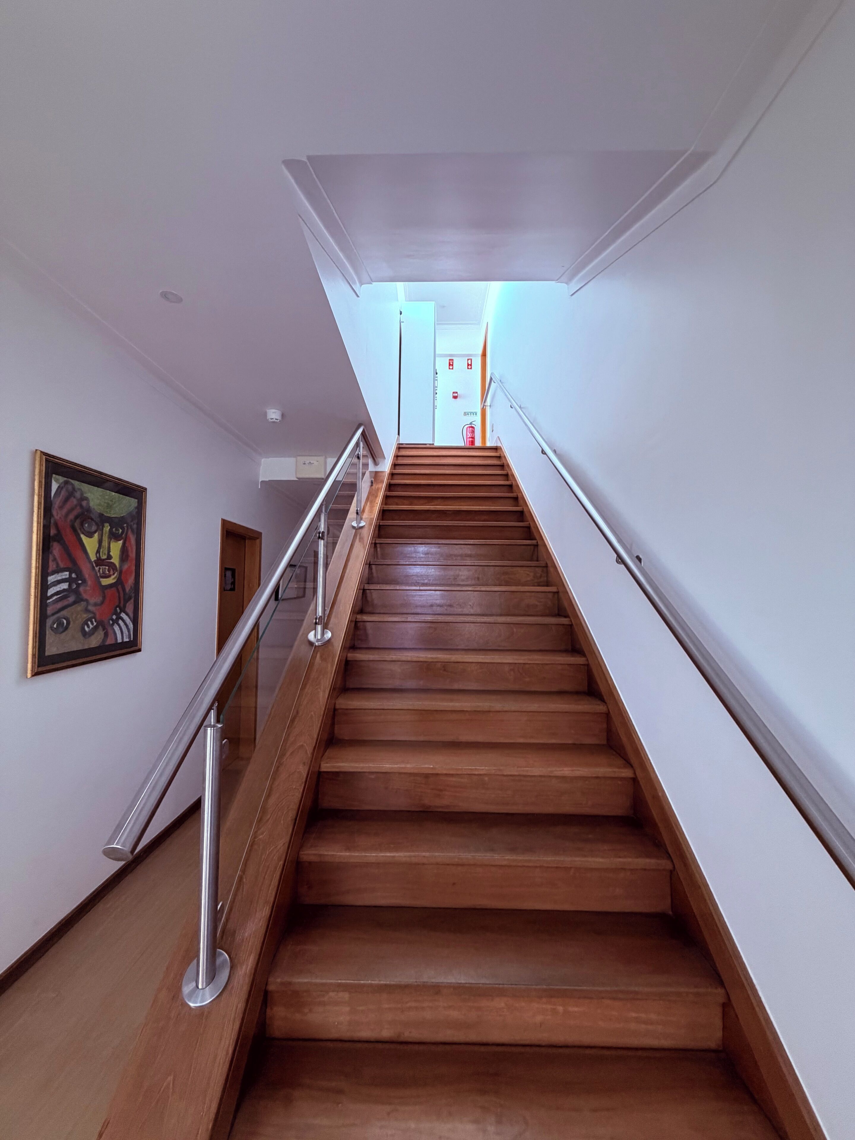 A wooden staircase with glass railings leading to a door at the top.