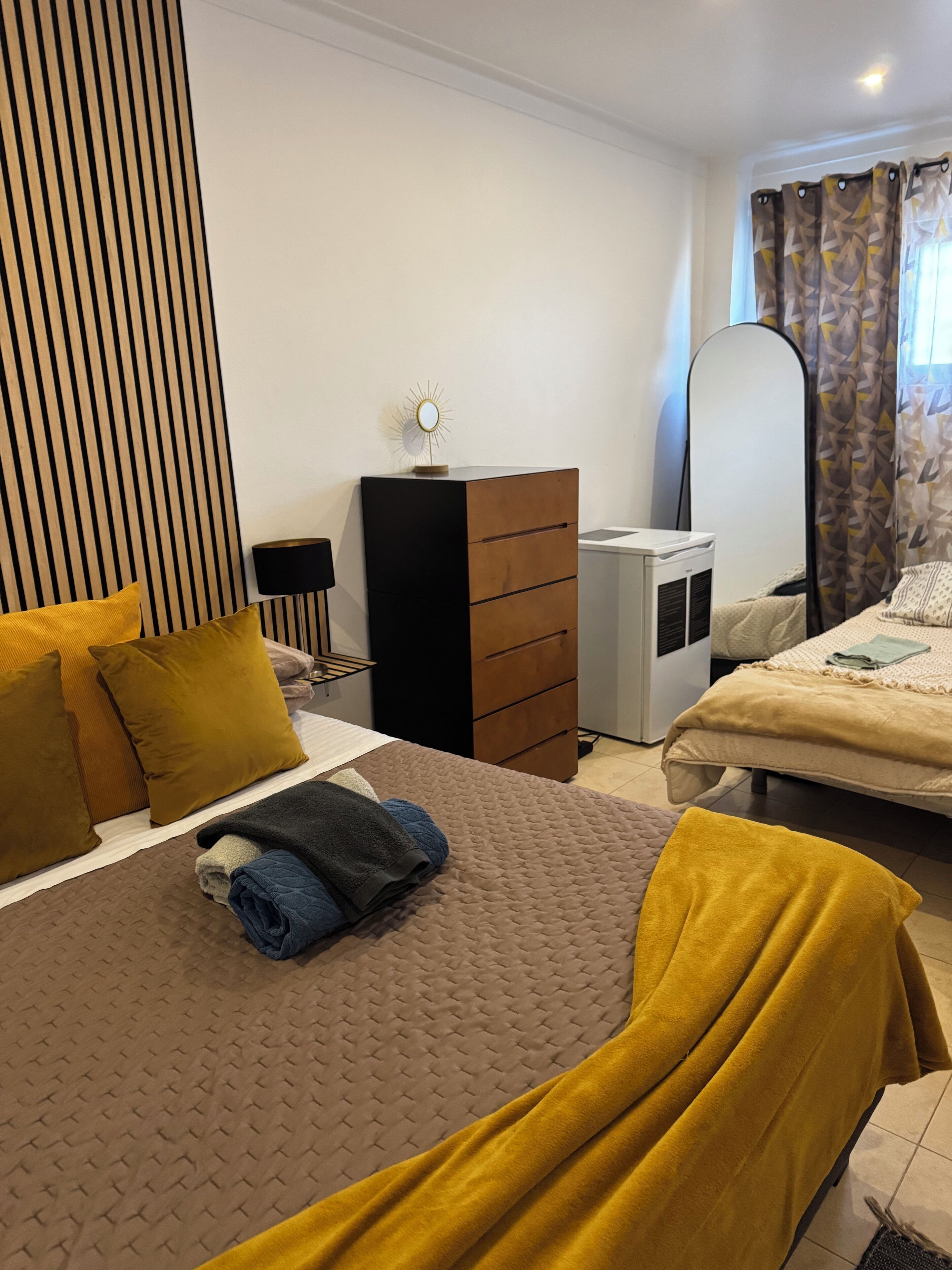 A bedroom with a bed, a dresser, a desk, and a mirror.