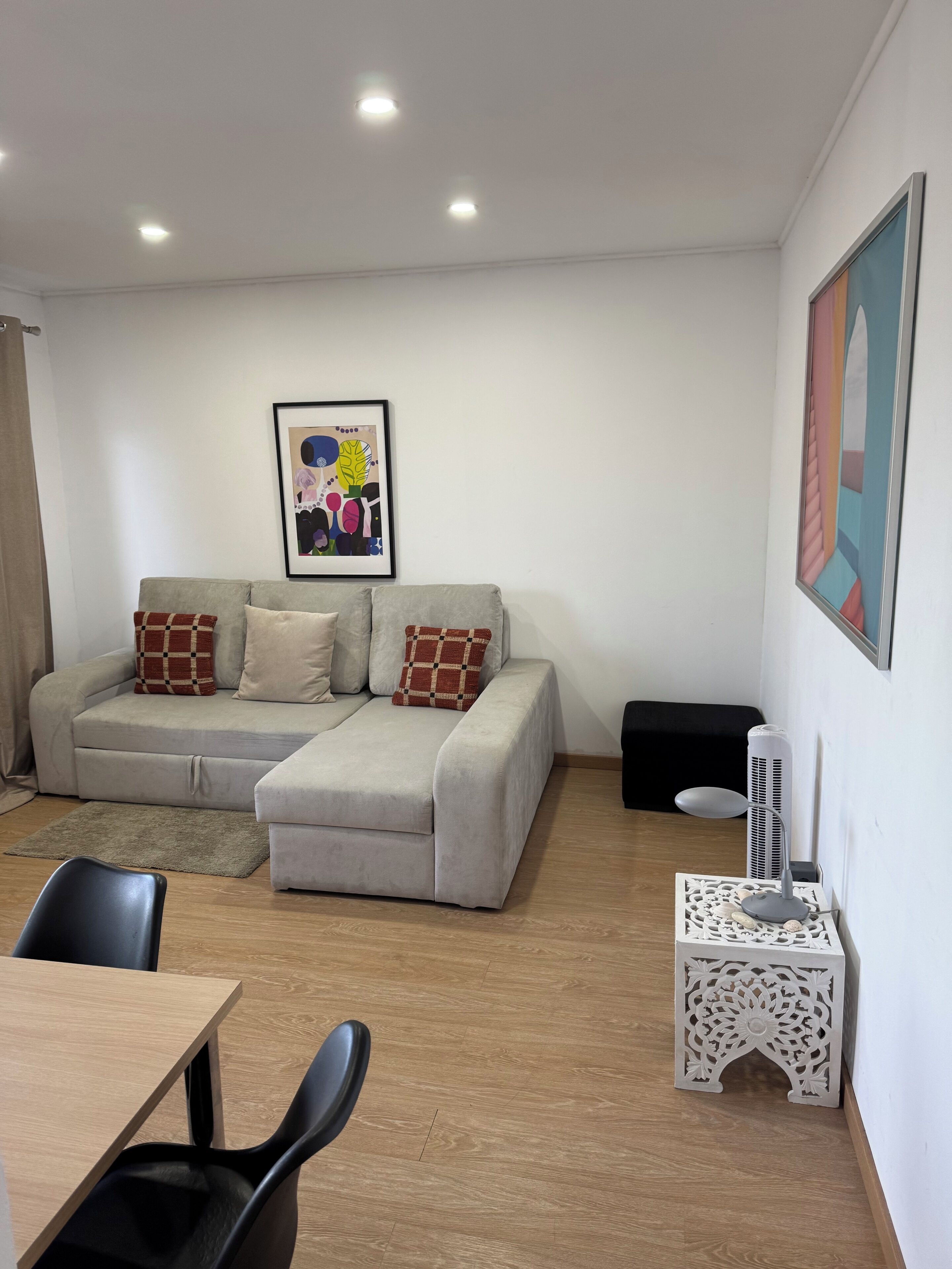 A modern living room with a sofa, a dining table, and a small decorative table.
