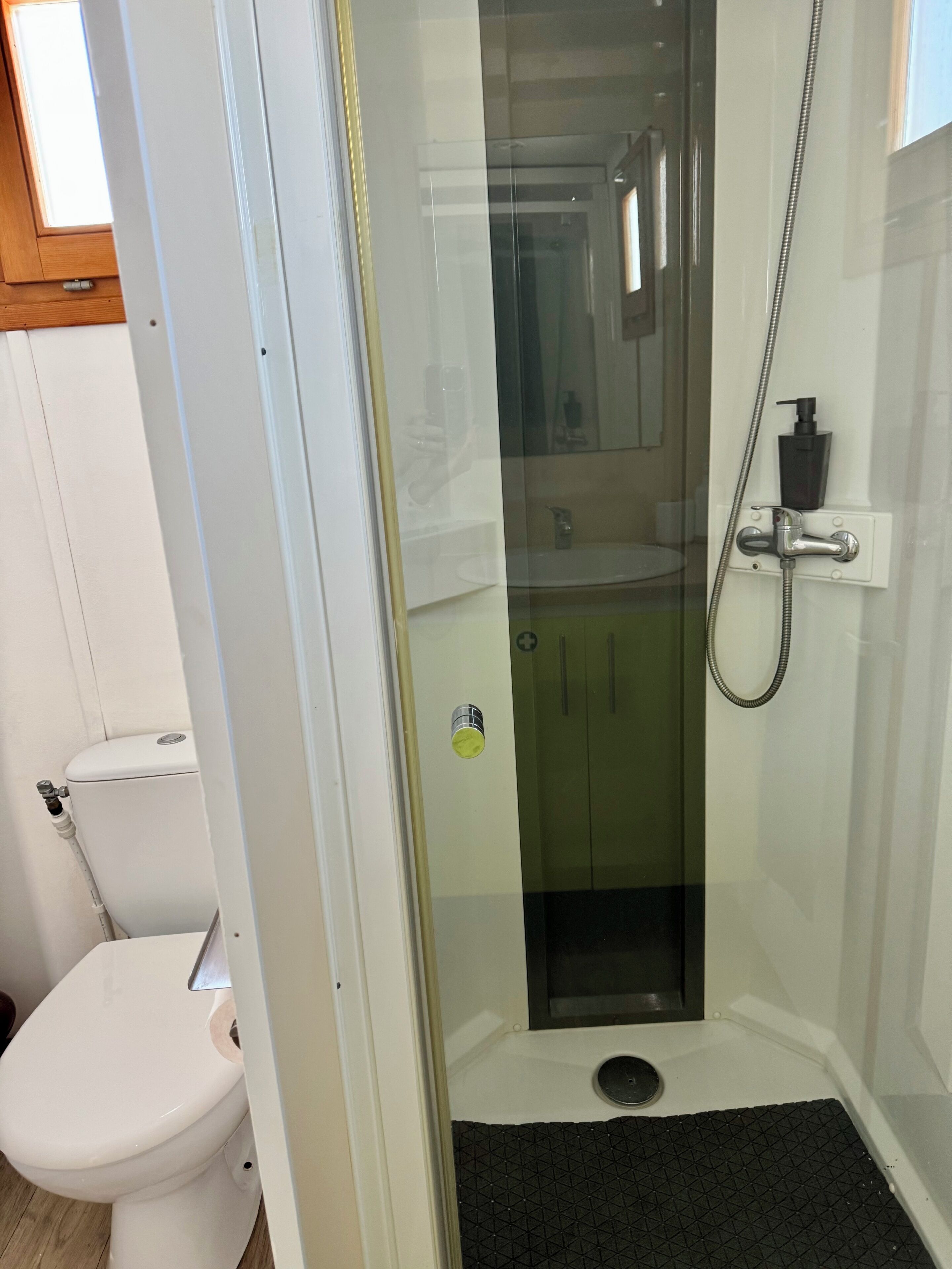 A bathroom with a glass-enclosed shower, a toilet, and a sink.