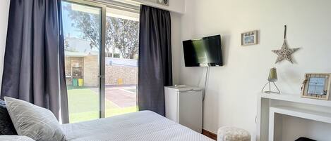 A bedroom with a bed, a TV, a fireplace, and a view of the outside.