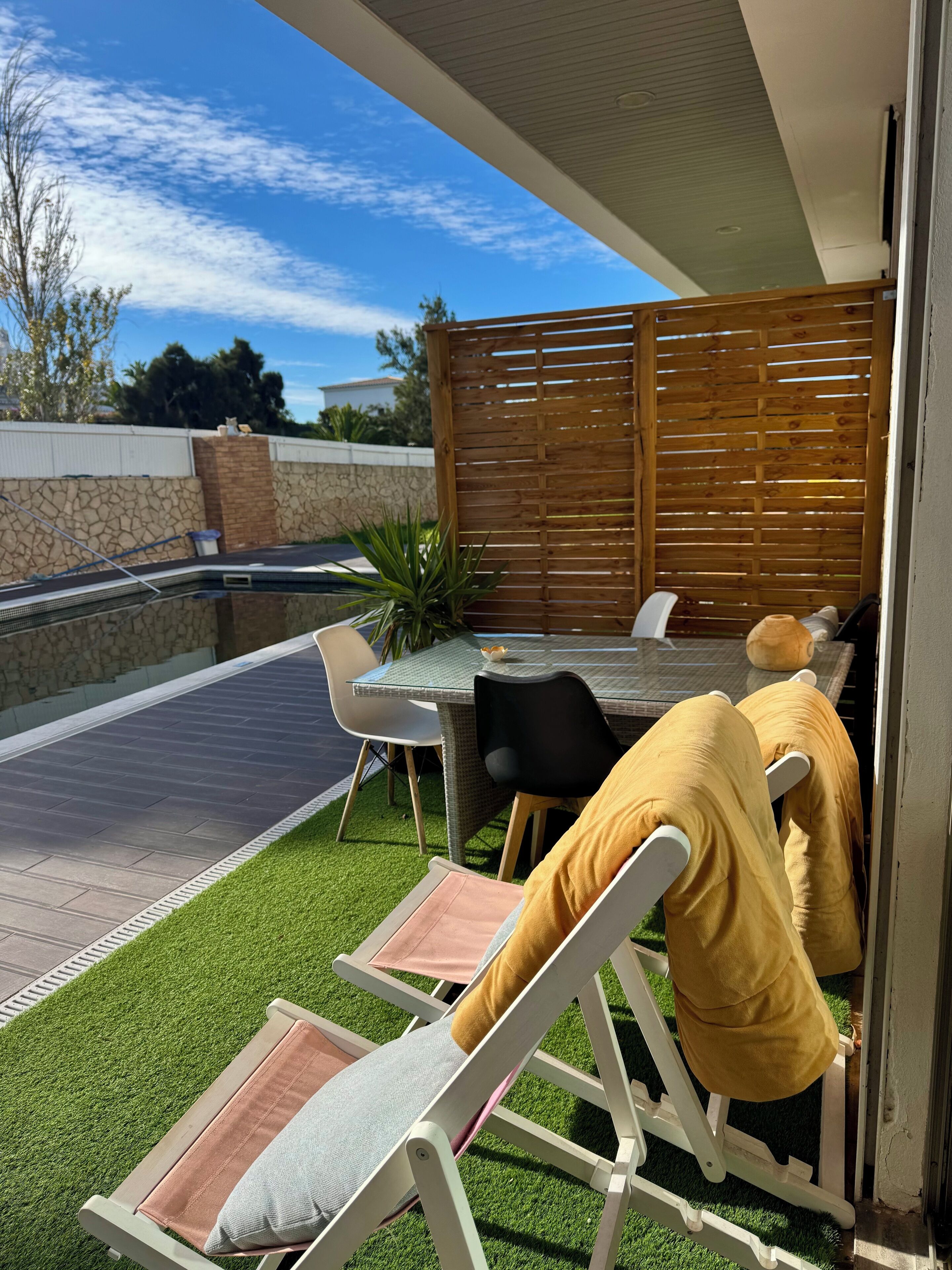 A patio area with a table and chairs, a small pool, and artificial grass.