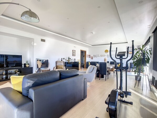A modern living room with a sofa, TV, and exercise equipment.