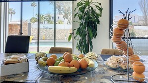 Zona pranzo con tavolo apparecchiato per la colazione, con frutta e pasticceria.
