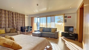 Una camera d'hotel moderna con un letto grande, una poltrona, una televisione e una scrivania.