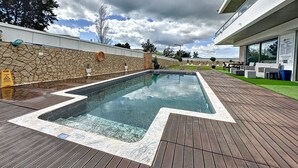 Una piscina con muretto in pietra e terrazza in legno.