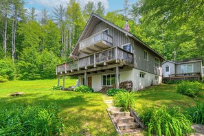 A two-story cabin with a balcony, surrounded by lush greenery and trees. - Amazing View: Townshend Escape Off the Beaten Path (Townshend)