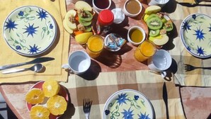 Een ontbijtsetting met borden, kommen en bekers op een tafelkleed.