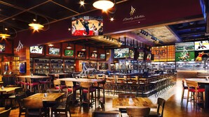 A spacious hotel bar with multiple screens displaying sports events, wooden tables and chairs, and a variety of seating options. - Amalz # 4, MGM Signature 2 Bedroom 3 Bathroom Balcony Suites ! (Las Vegas)