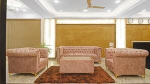 A living room with a tufted sofa set, a coffee table, and two armchairs. - SYN Elite Residency (Hyderabad)