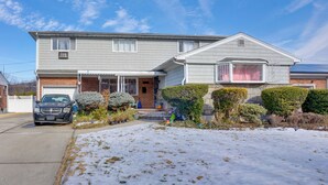 Ein zweistöckiges Haus mit Garage, Auffahrt und rasenbedeckter Schnee.
