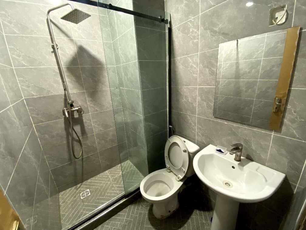 A bathroom with a glass-enclosed shower, a toilet, and a sink.