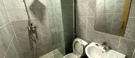A bathroom with a glass-enclosed shower, a toilet, and a sink.