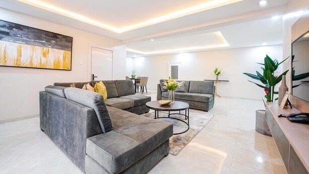 Een moderne woonkamer met grijze banken, een salontafel en een tv-meubel.