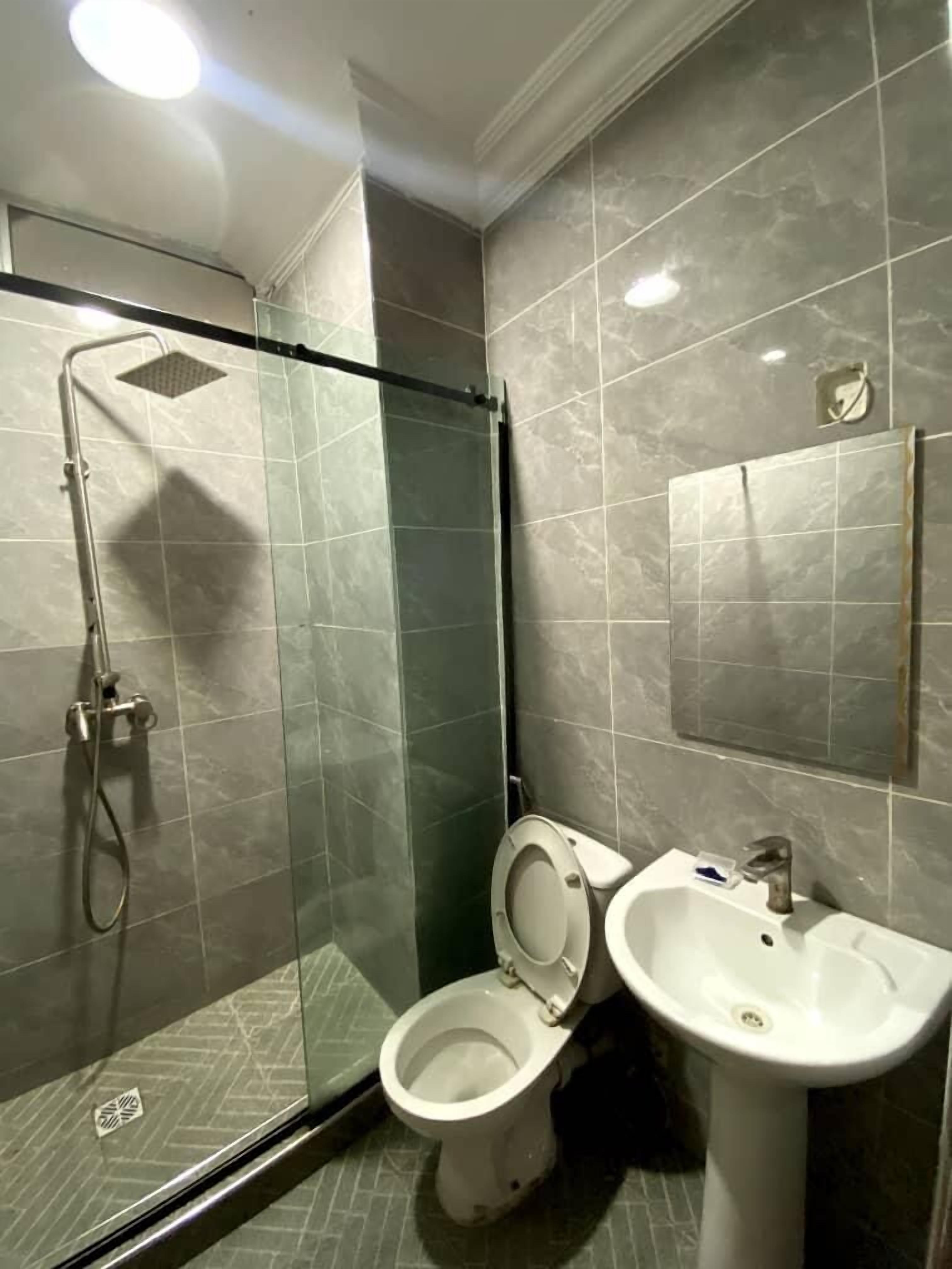A bathroom with a glass-enclosed shower, a toilet, and a sink.