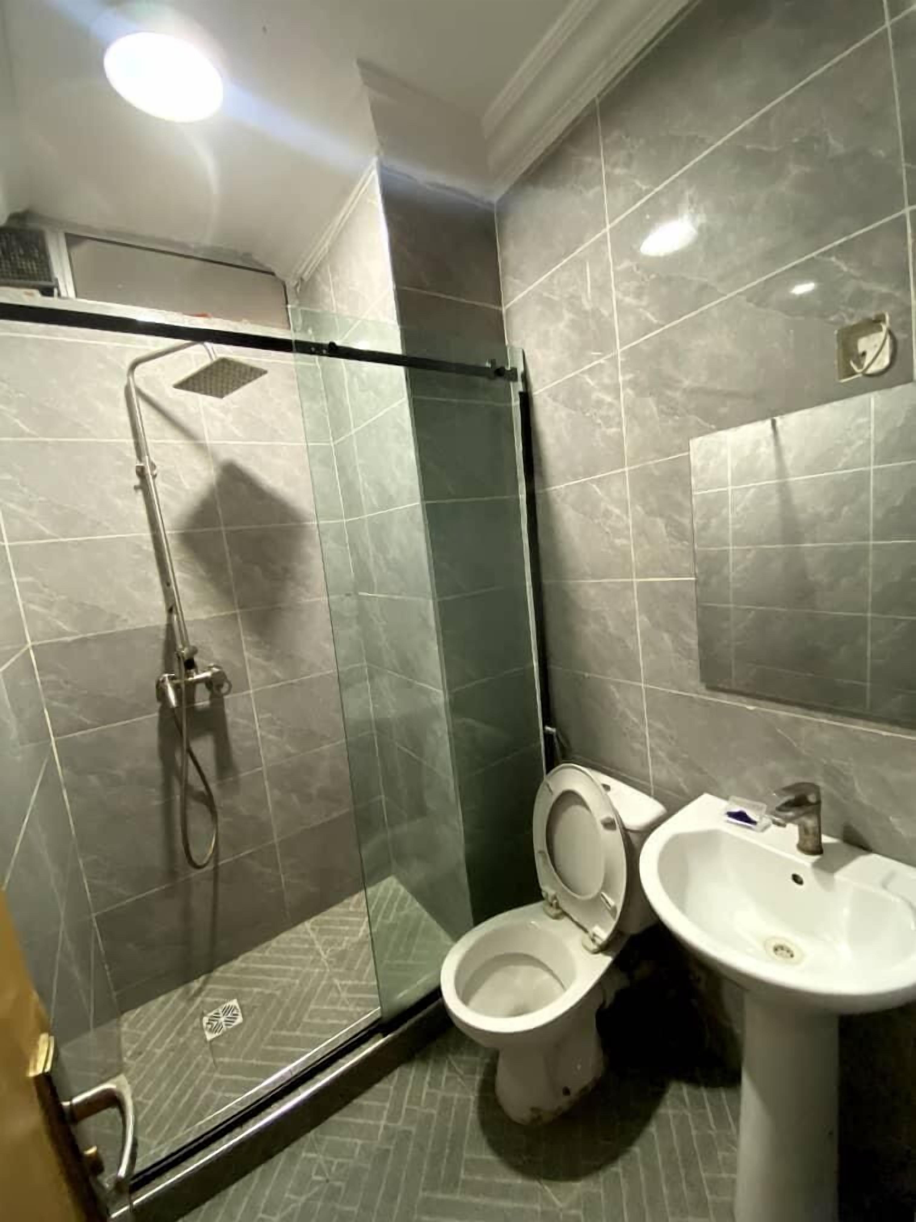A bathroom with a glass-enclosed shower, a toilet, and a sink.