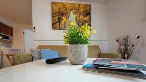 A living room with a sofa, a remote control, a vase with flowers, and a magazine on the table. - Logis near university, parking & Wi-Fi (Rouyn-Noranda)