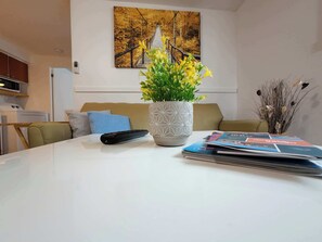 A living room with a sofa, a remote control, a vase with flowers, and a magazine on the table. - Logis near university, parking & Wi-Fi (Rouyn-Noranda)